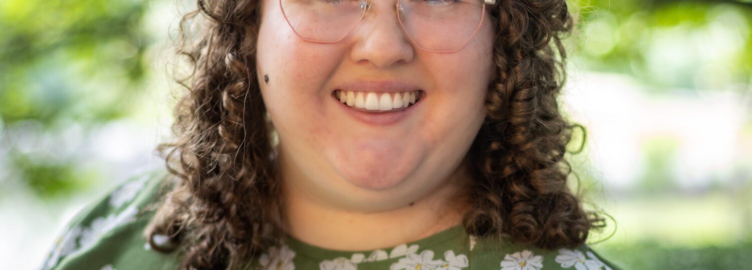 Headshot of Daumen wearing a green and white floral top.
