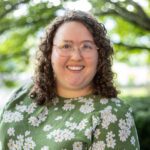 Headshot of Daumen wearing a green and white floral top.