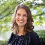 Headshot of Dobbins wearing a black top with a nature background.