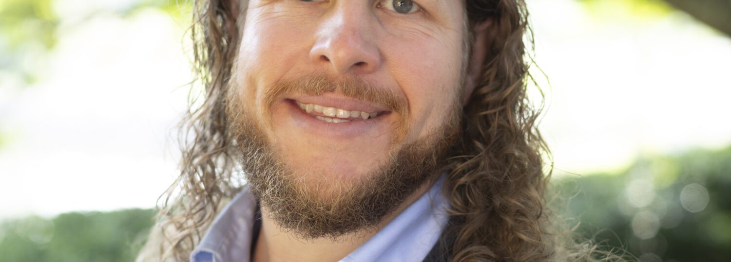 Headshot of Ingram wearing a blue blazer and a button up shirt without a tie.