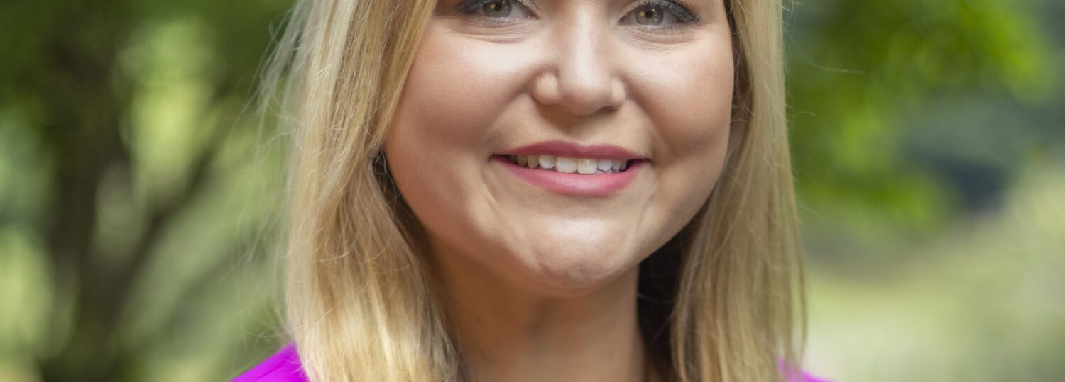 Headshot of Laws wearing a dark pink blazer and a black top.