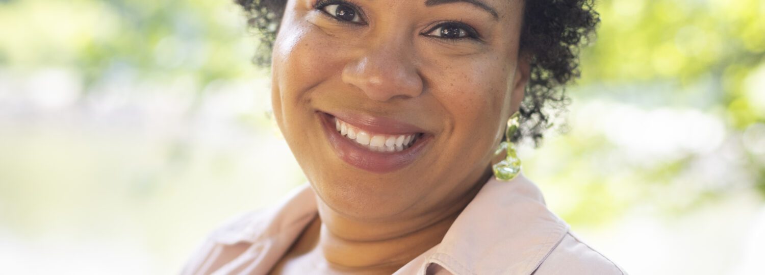 Headshot of Lofters wearing a pale pink blazer over a black and white striped top.