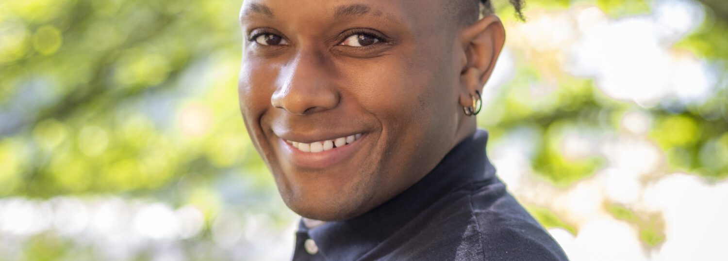 Headshot of Ormond wearing a black shirt with a collar.