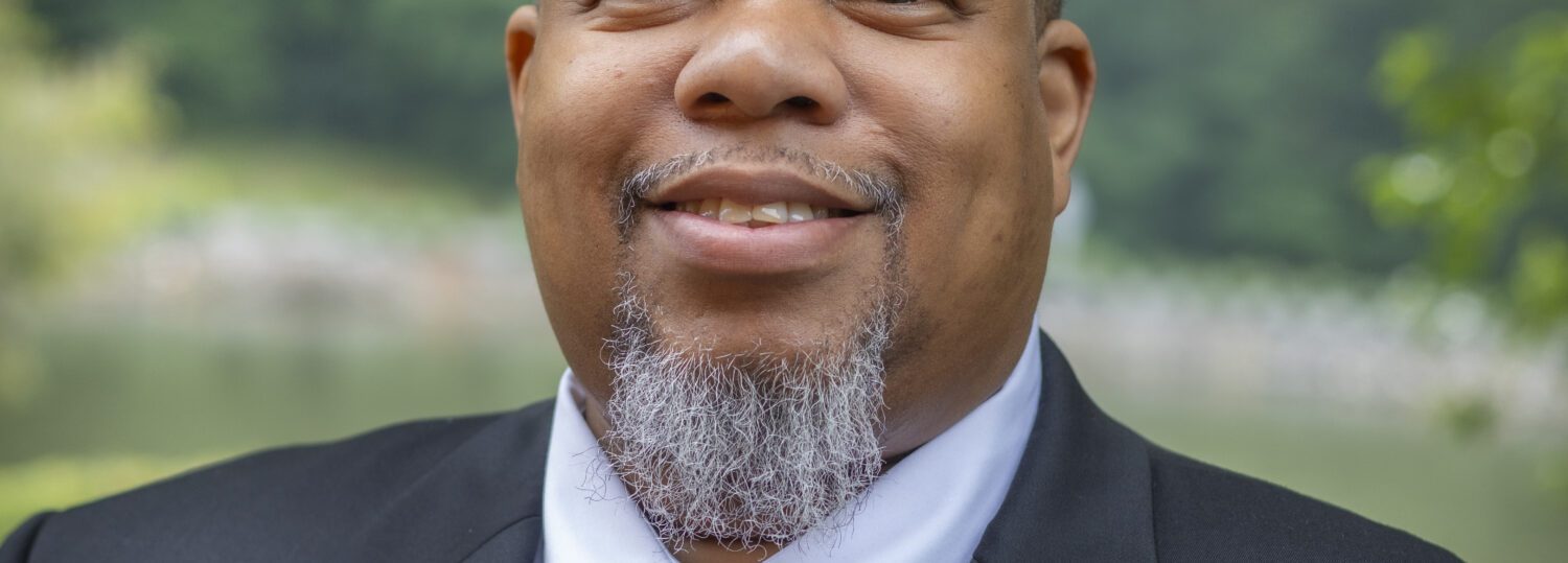 Headshot of Purdie wearing a gray blazer and a blue tie.