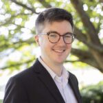 Headshot of Steitz wearing a black blazer over a light colored button up shirt.