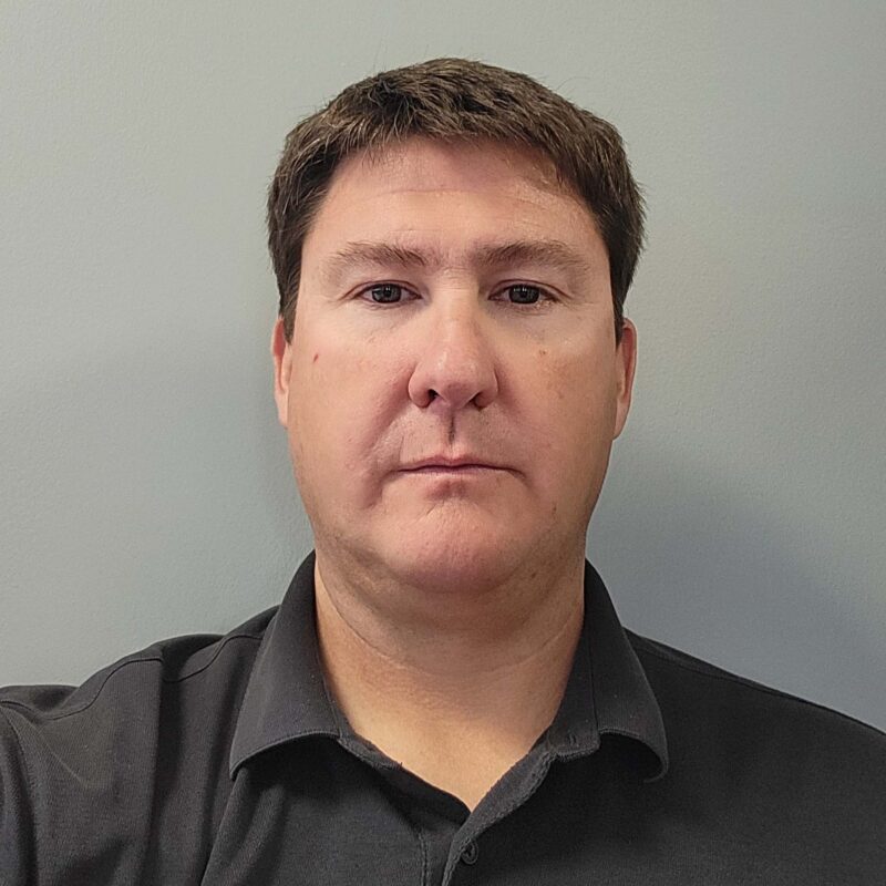 Adam Chacon headshot on a gray background.