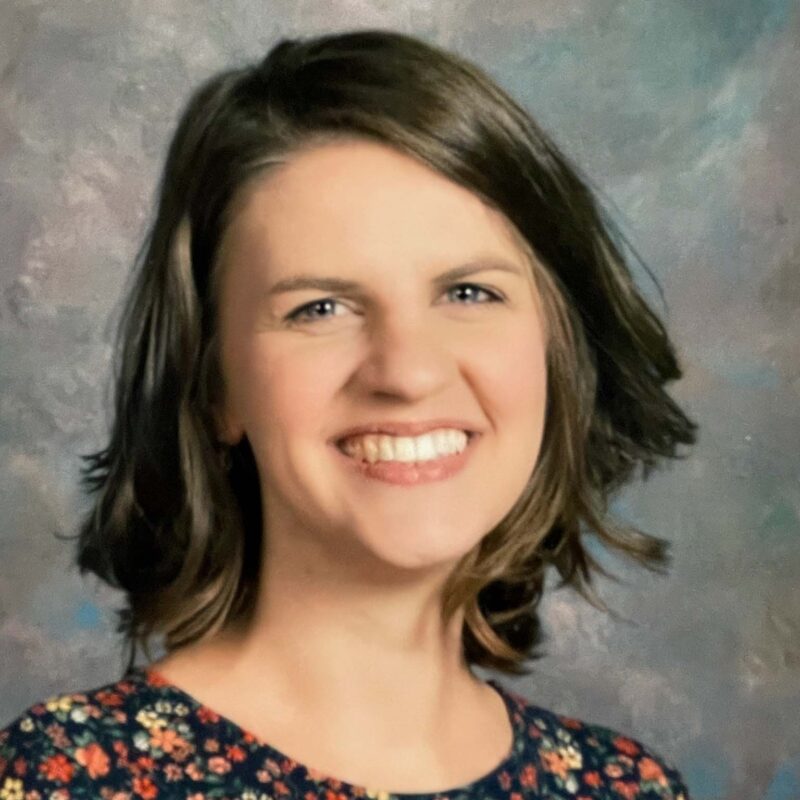 Headshot of Carrie Dobbins on a gray background.