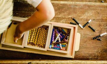 Hands of a child manipulating educational materials to learn to count in a Montessori classroom.